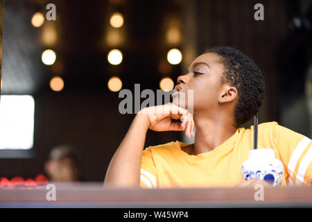 Jeune femme noire avec les cheveux très courts en prenant un verre de thé froid. Banque D'Images