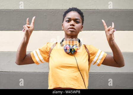 Jeune femme noire faisant le geste de les cornes avec ses mains à l'extérieur. Banque D'Images