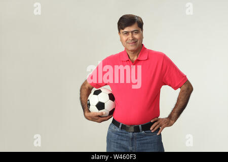 Portrait d'un homme tenant un ballon de soccer et souriant Banque D'Images