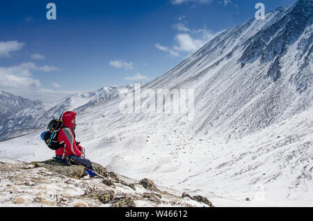 homme alpiniste assis sur une montagne enneigée en hiver ensoleillé jour Banque D'Images