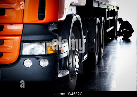 Mécanicien automobile Contrôle des pneus et la réparation des tracteurs routiers semi brisée dans le garage, selective focus. Banque D'Images