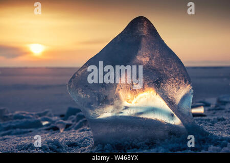 Belle glace transparente du lac Baikal contre le bleu foncé ciel orange et soleil éclatant Banque D'Images