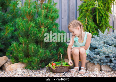 Cute little girl recueille les concombres et tomates de serre en Banque D'Images