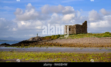 McCarthy Mor Tower House, Ballinskelligs Château avec figure solitaire se tient à proximité. Baile Sceilg, comté de Kerry, Irlande Banque D'Images