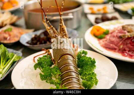 Gros plan d'un homard avec persil et autres flous aliments et salades en arrière-plan Banque D'Images