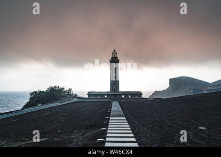 Vue sur volcan Capelinhos, phare de Ponta dos Capelinhos sur la côte ouest sur l''île de Faial, Açores, Portugal avec un coucher de soleil spectaculaire et fort Banque D'Images