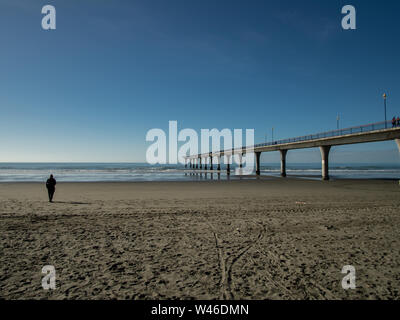 Une personne sur la plage par l'embarcadère à l'automne, avec un ciel bleu, New Brighton, New Zealand Banque D'Images