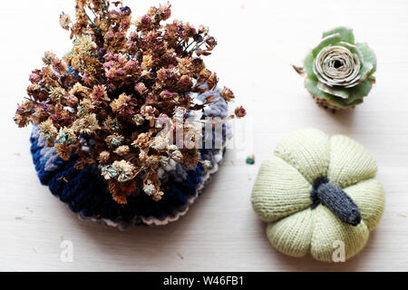 Close up daisy séchées fleurs en pot bleu en laine sur fond blanc, simple décor fait main sur table à la maison Banque D'Images