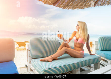 Femme tenant un délicieux cocktail aperol spritz glacé classique avec des cubes de glace sur une plage tropicale chaude dans le soleil d'été Banque D'Images