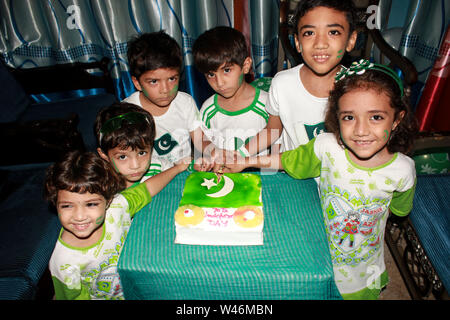 Enfants vêtus de couleurs vert et blanc robe et tenue en mains, drapeaux pakistanais Banque D'Images