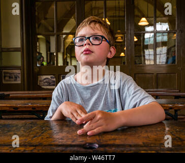 8 ans garçon attentionné, assis au bureau de la vieille école, Beamish Living Museum, County Durham, England, UK Banque D'Images