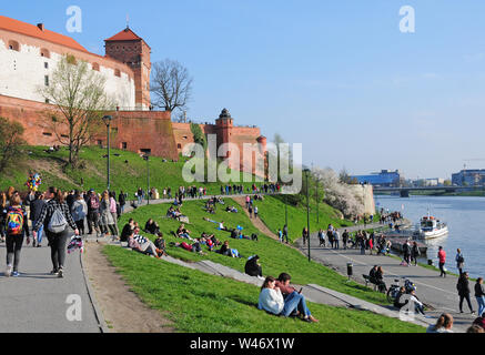 Dimanche après-midi. Les personnes bénéficiant du soleil au début du printemps par le Château Royal de Wawel et la Vistule, Cracovie, en Petite Pologne. Banque D'Images