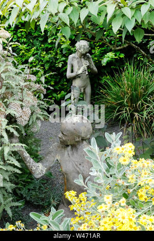 Deux statues de jardin, l'une étant Pan jouant ses pipes, dans un jardin de campagne anglaise, UK - John Gollop Banque D'Images