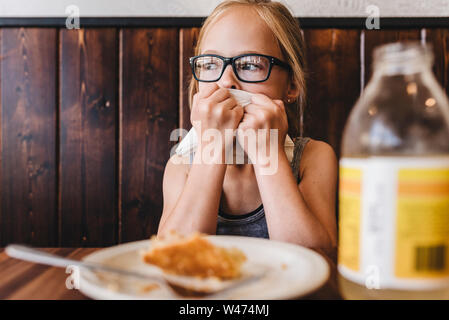 Petite fille mange et boit à table dans un café restaurant Banque D'Images