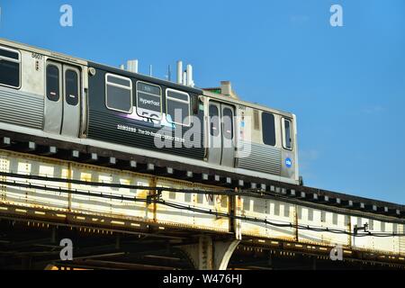 Chicago, Illinois, USA. Un CTA ligne rouge du train ornée avec la publicité traverse sur Clark Street à Chicago's Lakeview quartier. Banque D'Images