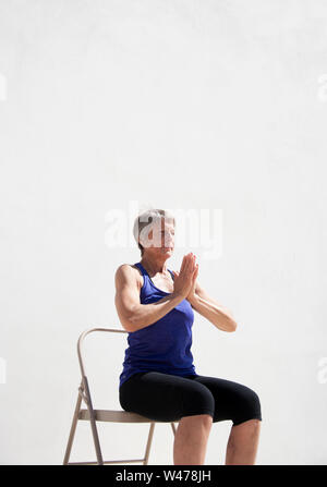 Practing mature woman gentle restorative yoga pose photographiés dans un fond blanc. Banque D'Images