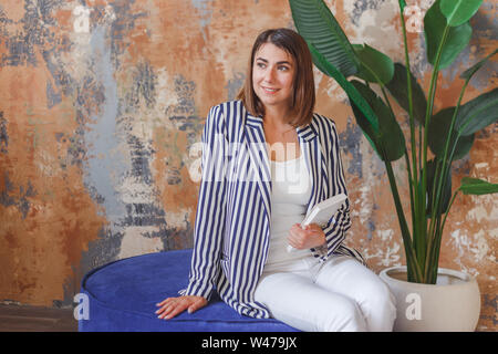 Woman in striped jacked posant devant de gros plant. Portrait intérieur intérieur Banque D'Images