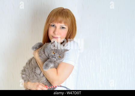 Belle femme d'âge moyen avec mignon British shorthair chat posant à la maison.Une femme dans la période de la ménopause. Cheveux rouge blonde mature senior female r Banque D'Images