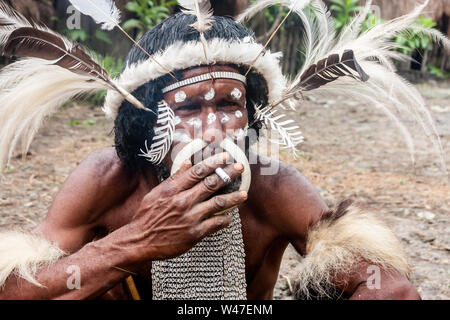 Wamena, Indonésie - 9 janvier 2010 : le chef de la tribu Dani dans une robe traditionnelle de fumer une cigarette en Dugum Dani Village. Baliem Valley Papouasie Banque D'Images