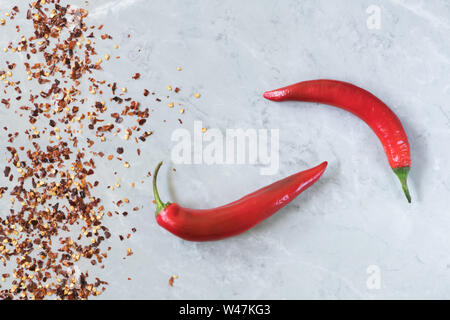 Deux hot chili peppers sur fond de marbre gris, l'utilisation de sauce harissa en arabe, en géorgien sause adjika. Il peperoncino italien bio par Calabria Banque D'Images