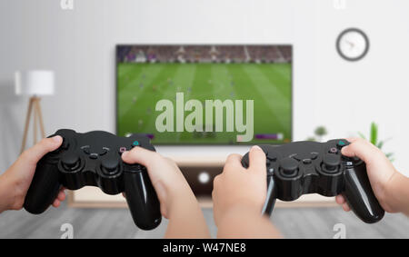 Les garçons jouent au football sur la console de jeux sur un grand plat dans la chambre. La notion de plaisir et des jeux pour les amis. Banque D'Images