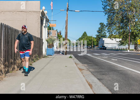 Un homme de race blanche d'âge moyen marche dans un trottoir porter du rouge, blanc et bleu short dans un modèle similaire à un drapeau américain. Banque D'Images