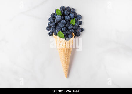 Les bleuets à la menthe dans waffle ice cream cone sur fond de marbre blanc. été food concept. vue d'en haut. télévision lay Banque D'Images