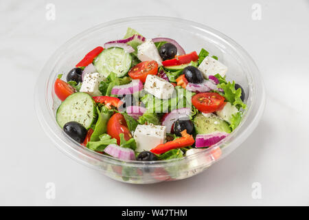 Salade grecque sains en emballage en plastique pour emporter ou livraison de nourriture sur une base en marbre blanc. close up Banque D'Images