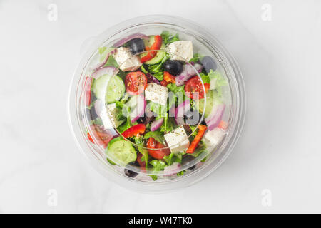 Salade grecque sains en emballage en plastique pour emporter ou livraison de nourriture sur un fond blanc en vue de dessus. Banque D'Images