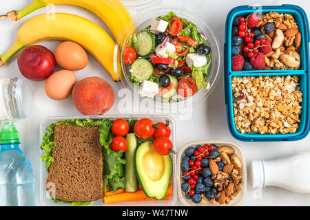 Assortiment de boîtes à lunch avec des aliments sains à emporter pour l'ensemble de la journée. Petit-déjeuner muesli avec du yaourt, salade grecque, sandwich, fruits et légumes wi Banque D'Images