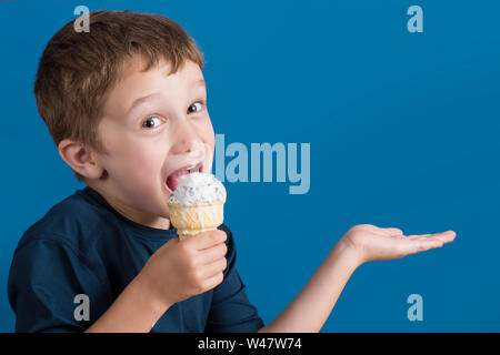 Boy eating an ice cream cone sur fond bleu Banque D'Images
