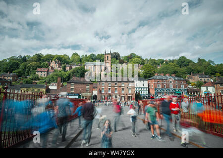 Village britannique historique avec une foule de personnes en mouvement flou traversant le pont à la lumière du soleil. Ironbridge à Shropshire, Royaume-Uni Banque D'Images