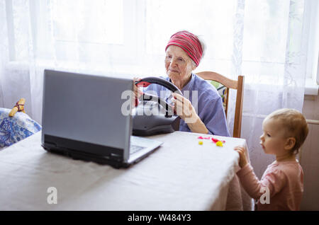 Senior woman jeu vidéo sur ordinateur portable, tandis que son arrière-petite-fille La regarder jouer à la maison Banque D'Images