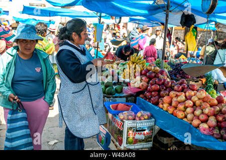 PISAC, PÉROU - 30 avril 2012 : Un vendeur de fruits un morceau de pastèque tranches sur le marché de pisac dans la Vallée Sacrée des Incas au Pérou. Banque D'Images