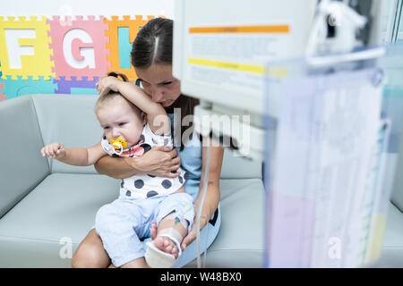 Face à une mère triste et pleurer ma petite fille à l'hôpital. Petite fille est injecté. Compte-gouttes intraveineuse médical de l'égouttement, slow motion, close-up Banque D'Images