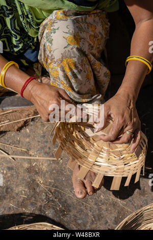 Femme indienne tisse un panier de bambou avec ses jambes et ses bras dans un marché local, Close up. L'Inde Banque D'Images