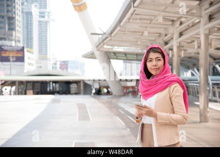 Belle femme arabe moderne porte le hijab à l'aide de téléphone mobile dans la grande ville. Banque D'Images