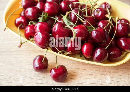 Fruits rouges juteux mûr de la cerise dans un plat sur une table en bois. Vue supérieure, close-up Banque D'Images