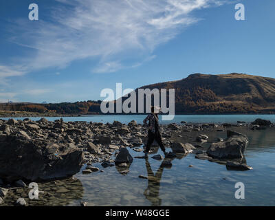 Une personne sur la rive du lac Tekapo, Nouvelle-Zélande, avec de l'eau bleu turquoise Banque D'Images