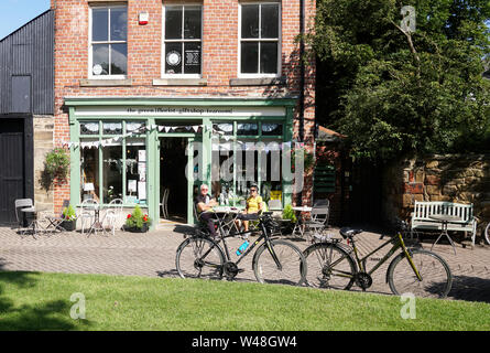 Un couple plus âgé de cyclistes s'assoient à l'extérieur du magasin de thé de Washington Village avec leurs vélos garés, au nord-est de l'Angleterre, au Royaume-Uni Banque D'Images