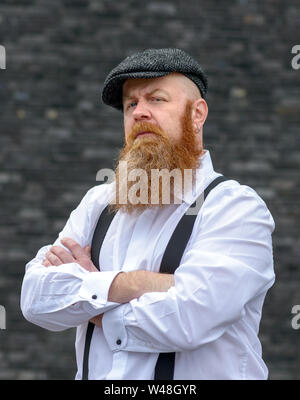 Portrait d'un homme barbu en surpoids et renforts de tissu hat standing with folded arms Banque D'Images