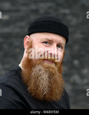 Portrait of a Happy redhead homme avec barbe touffue et les yeux bleus, portant un chapeau beanie Banque D'Images