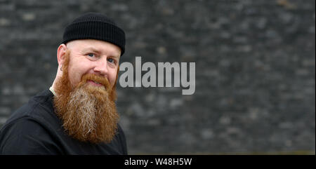 Heureux l'homme à barbe rousse touffue et les yeux bleus portant un Beanie Hat smiling at the camera with copy space Banque D'Images