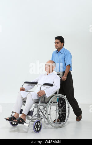 Ward boy pushing a senior man on a wheelchair Stock Photo