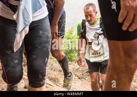 Les coureurs fatigués sous la pluie, l'escalade d'un cratère sur la piste d'un raide de les deux bras dans le cirque de Mafate lors du Grand Raid, la réunion Banque D'Images