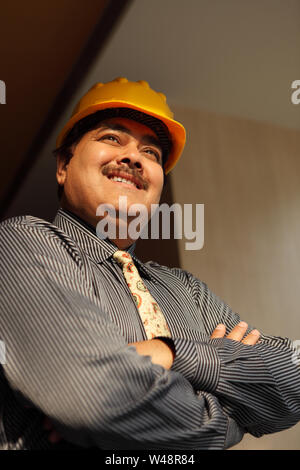 Low angle view of an Indian architect smiling with his arms crossed Banque D'Images