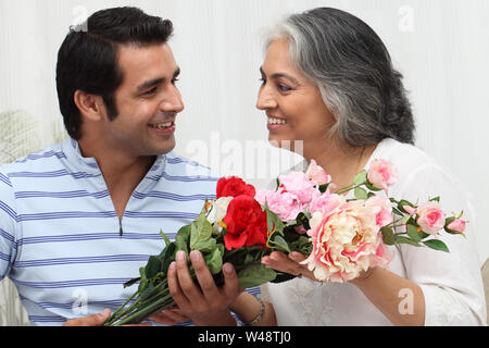 Indian man giving bouquet de fleurs à sa mère Banque D'Images