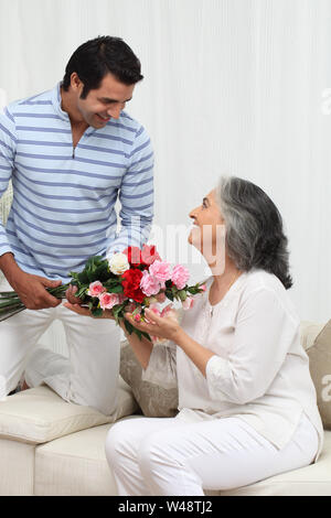 Homme donnant un bouquet de fleurs à sa mère Banque D'Images