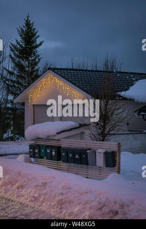 Tromso, Norvège - Décembre 2018 : rangée de boîtes aux lettres sur une clôture en bois en face d'un immeuble garage maison en hiver Banque D'Images