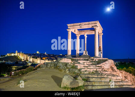 La lune s'élève au-dessus de la ville illuminée d'Avila et le monument Cuatro Postes, Avila, Espagne Banque D'Images